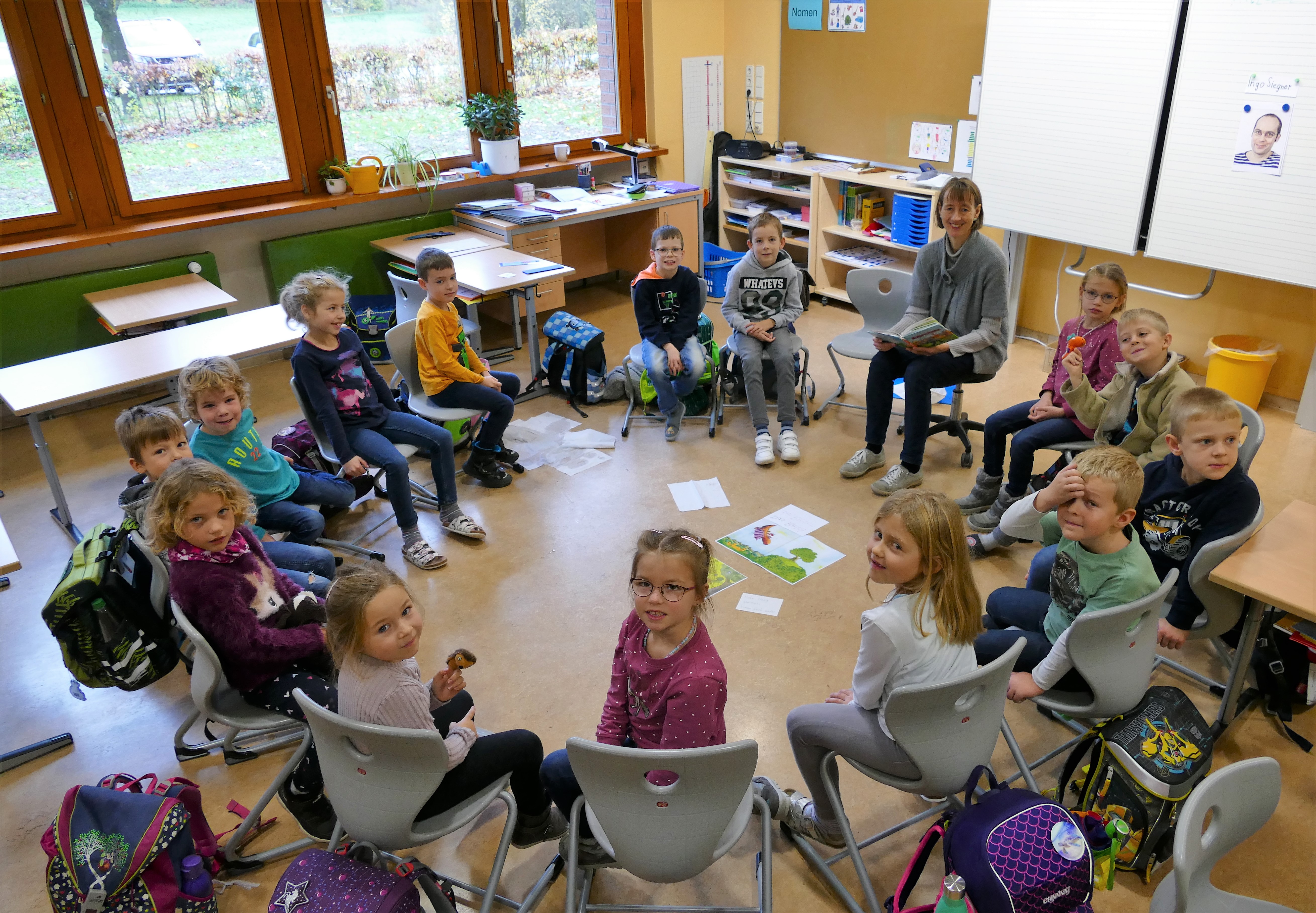 Kinder sitzen mit Lehrerin im Stuhlkreis